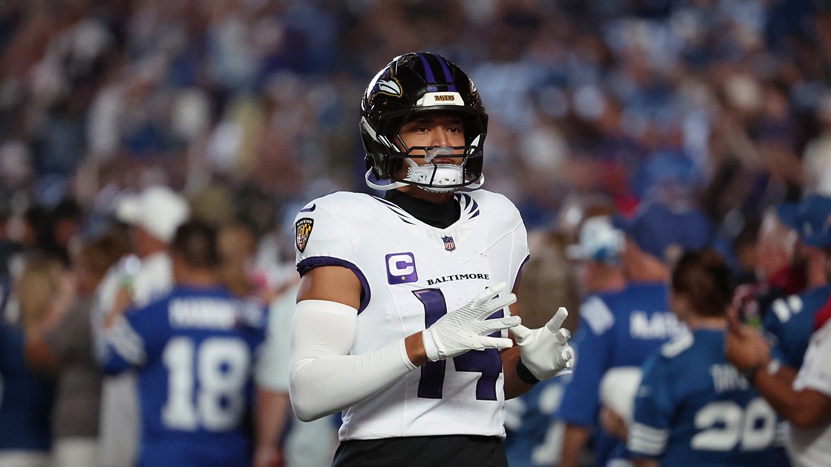 Baltimore Ravens safety Kyle Hamilton walks onto the field adjusting his gloves in a white Ravens road jersey.