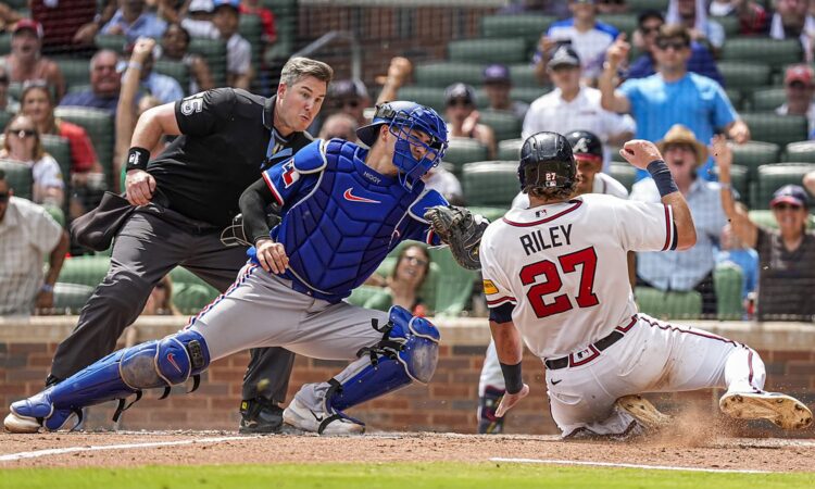 Texas Rangers catcher Kyle Higashioka, No. 11, applies a tag on sliding Atlanta Braves third baseman Austin Riley.