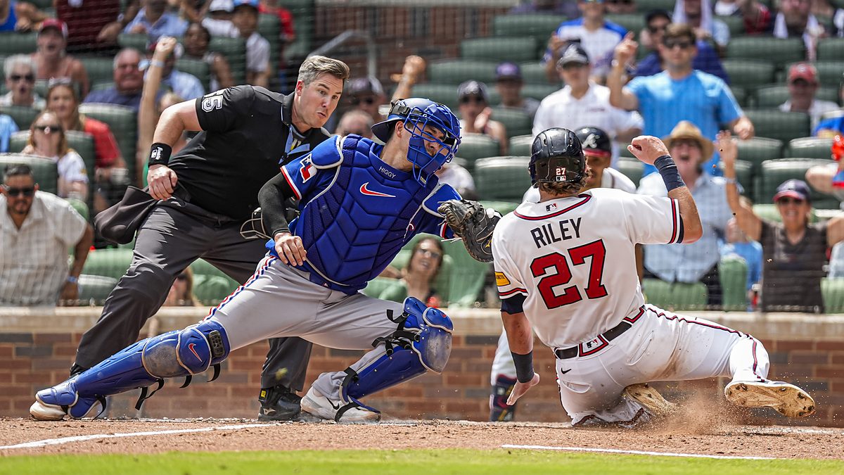 Texas Rangers catcher Kyle Higashioka, No. 11, applies a tag on sliding Atlanta Braves third baseman Austin Riley.