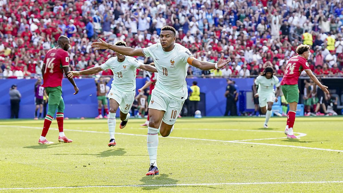 France forward Kylian Mbappé runs with both arms outstretched to celebrate against Morocco as teammates chase him.