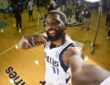 Dallas Mavericks guard Kyrie Irving smiles and points at himself while holding the camera at arm's length on the practice court.