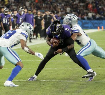 Cowboys safety Caleb Downs wraps up Ravens quarterback Lamar Jackson as cornerback Shavon Revel Jr. closes in near the sideline.