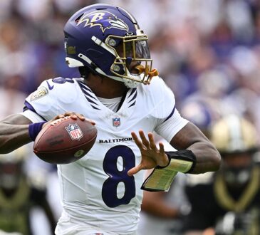 Baltimore Ravens quarterback Lamar Jackson cocks the ball back to throw with a Saints defender blurred behind him.
