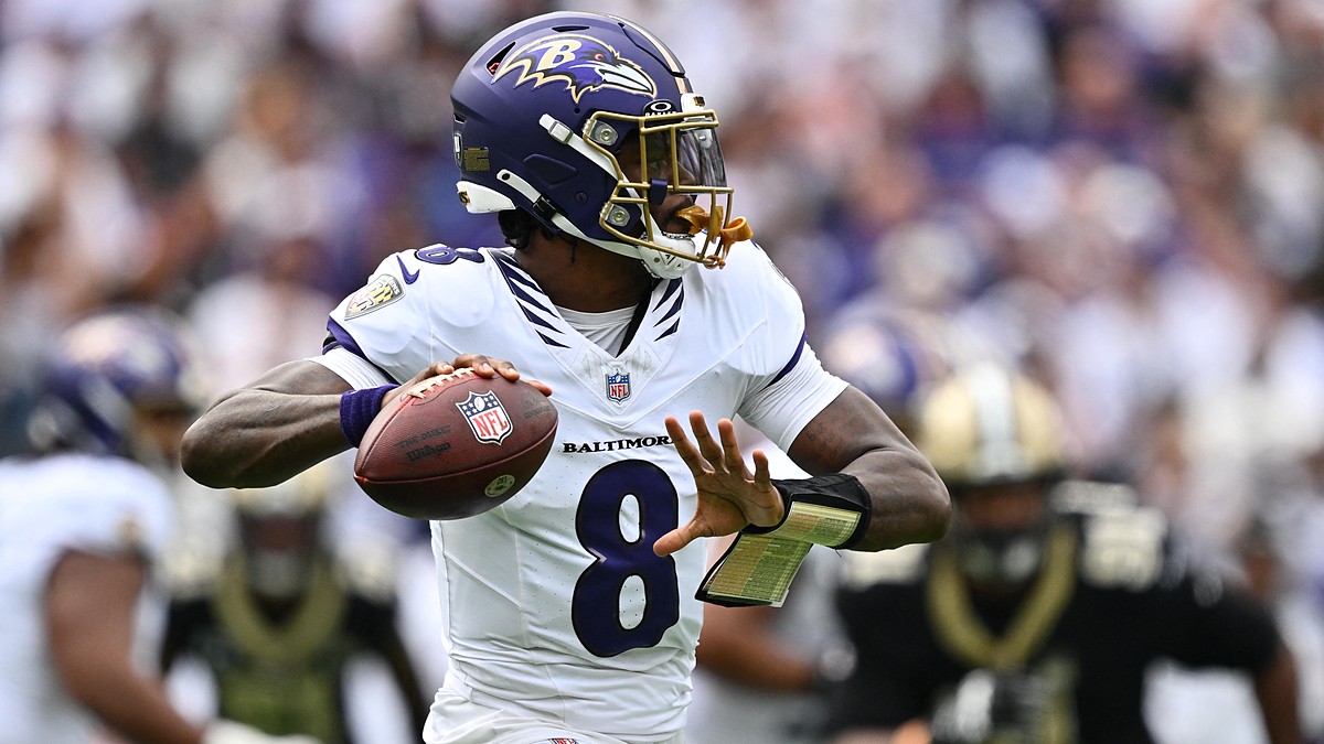 Baltimore Ravens quarterback Lamar Jackson cocks the ball back to throw with a Saints defender blurred behind him.