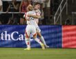 FC Dallas forward Logan Farrington is lifted by a teammate while celebrating a goal in front of St. Louis supporters.