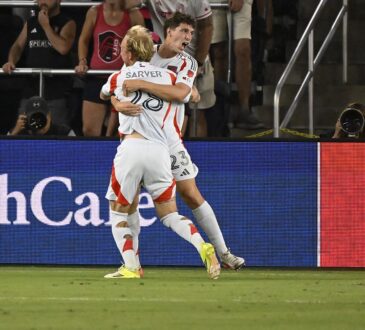 FC Dallas forward Logan Farrington is lifted by a teammate while celebrating a goal in front of St. Louis supporters.