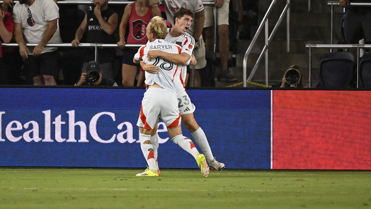 FC Dallas forward Logan Farrington is lifted by a teammate while celebrating a goal in front of St. Louis supporters.