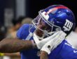 New York Giants wide receiver Malik Nabers, No. 1, brings a gloved hand to his facemask while celebrating.