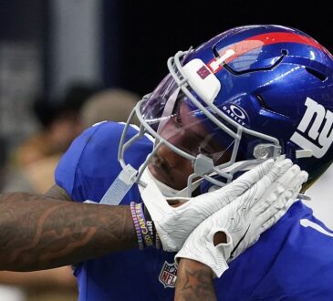 New York Giants wide receiver Malik Nabers, No. 1, brings a gloved hand to his facemask while celebrating.