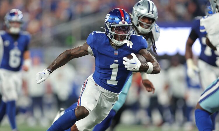 New York Giants wide receiver Malik Nabers runs upfield with the ball as a Cowboys defender pursues him.