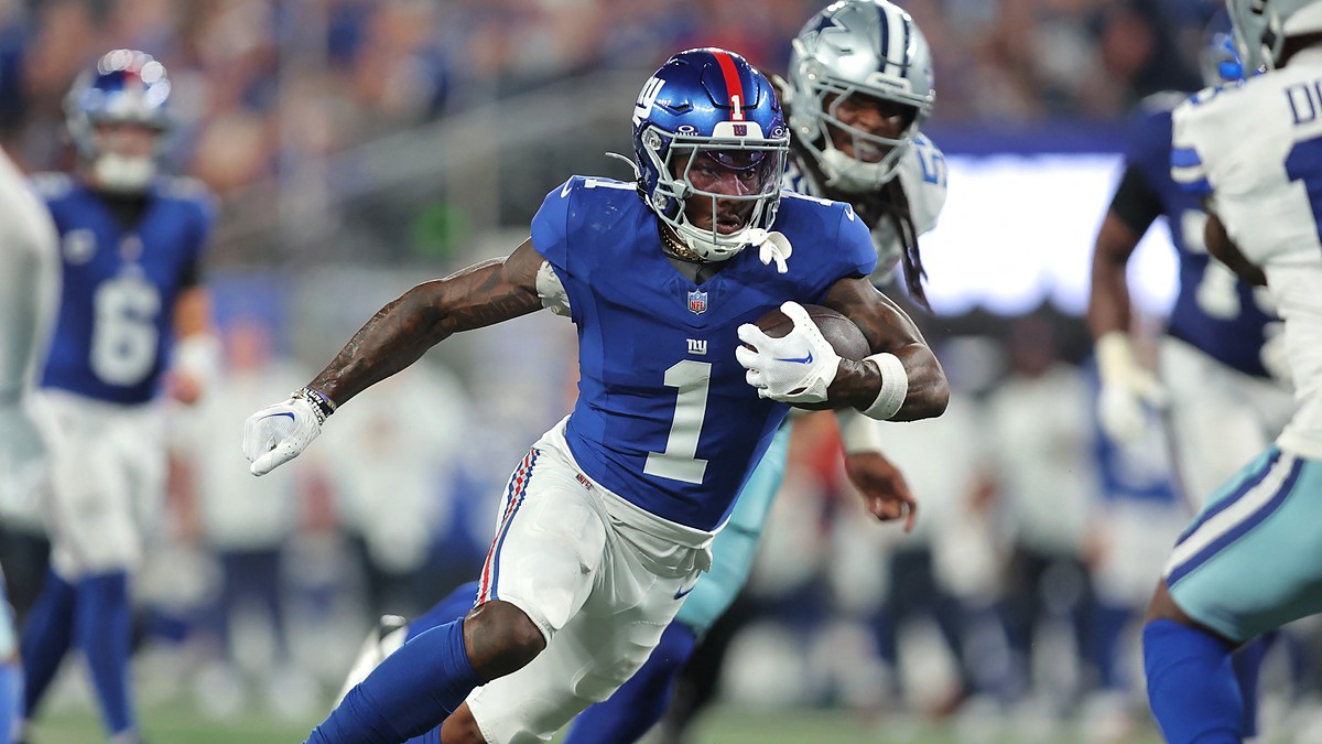 New York Giants wide receiver Malik Nabers runs upfield with the ball as a Cowboys defender pursues him.