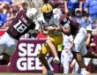 Texas A&M defensive end Marco Jones wraps up Arizona State quarterback Cutter Boley as another Aggies defender closes in.