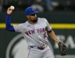 New York Mets second baseman Marcus Semien cocks his arm to make a throw in a gray Mets road uniform.