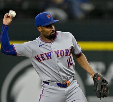 New York Mets second baseman Marcus Semien cocks his arm to make a throw in a gray Mets road uniform.