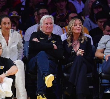 Mark Walter sits with his arms crossed next to Jeanie Buss in courtside seats at a Lakers game.