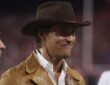 Actor Matthew McConaughey stands on the sideline in a brown hat and leather jacket before a Texas game.