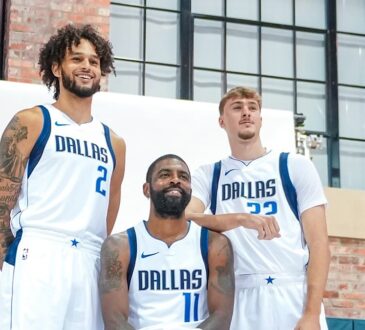 Dallas Mavericks center Dereck Lively II, guard Kyrie Irving, and forward Cooper Flagg pose together in a brick gym.