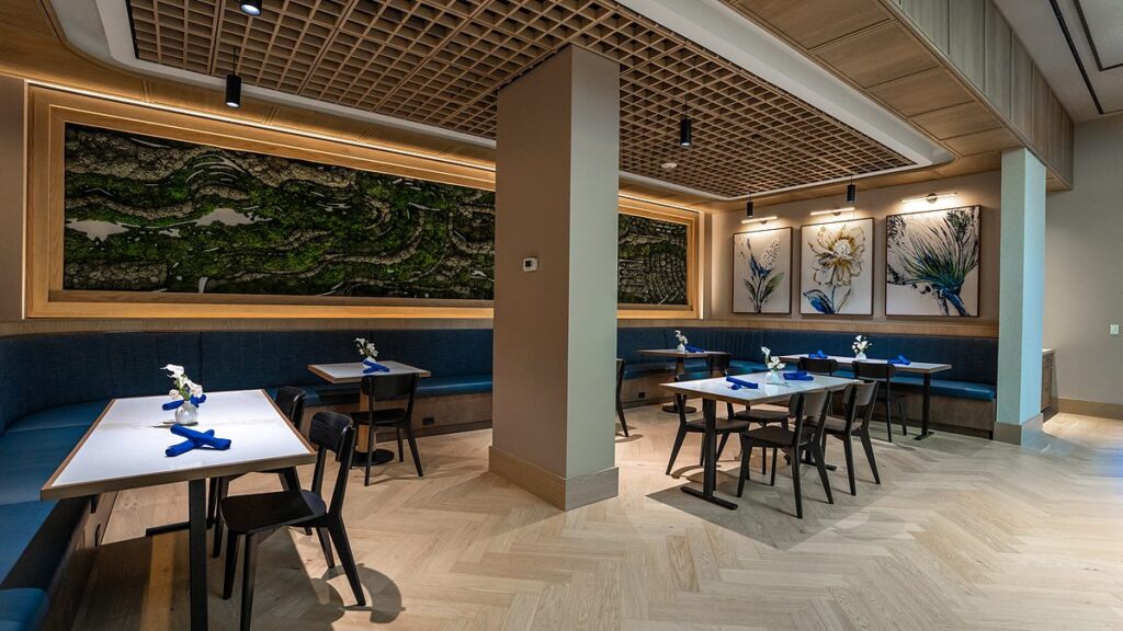Dallas Mavericks practice facility dining room tables set beside custom blue banquette seating under a wood-slat ceiling.
