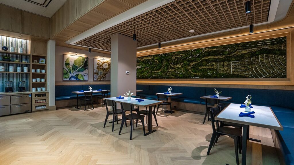 Dallas Mavericks practice facility dining room with a long preserved-moss mural above blue banquette seating.