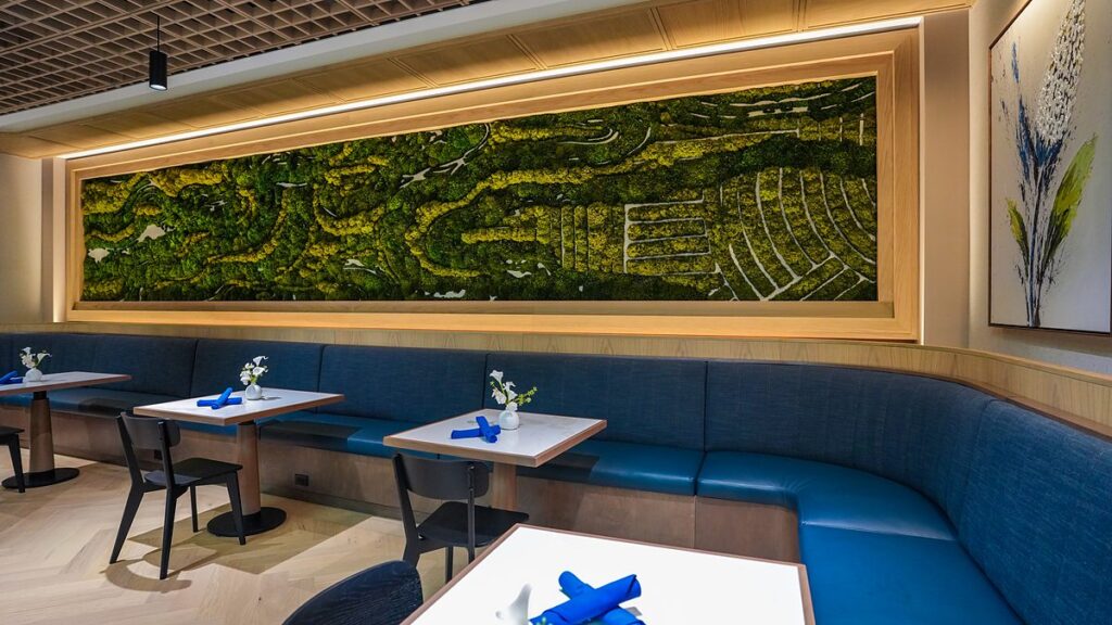 Dallas Mavericks practice facility dining room with a framed preserved-moss mural above curved blue banquette seating.
