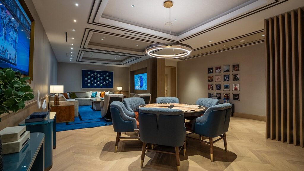 Dallas Mavericks players’ lounge with a card table in the foreground and a seating area and TVs beyond.