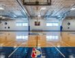 Dallas Mavericks practice court viewed from under a basket, with the NBA logo painted along the baseline.