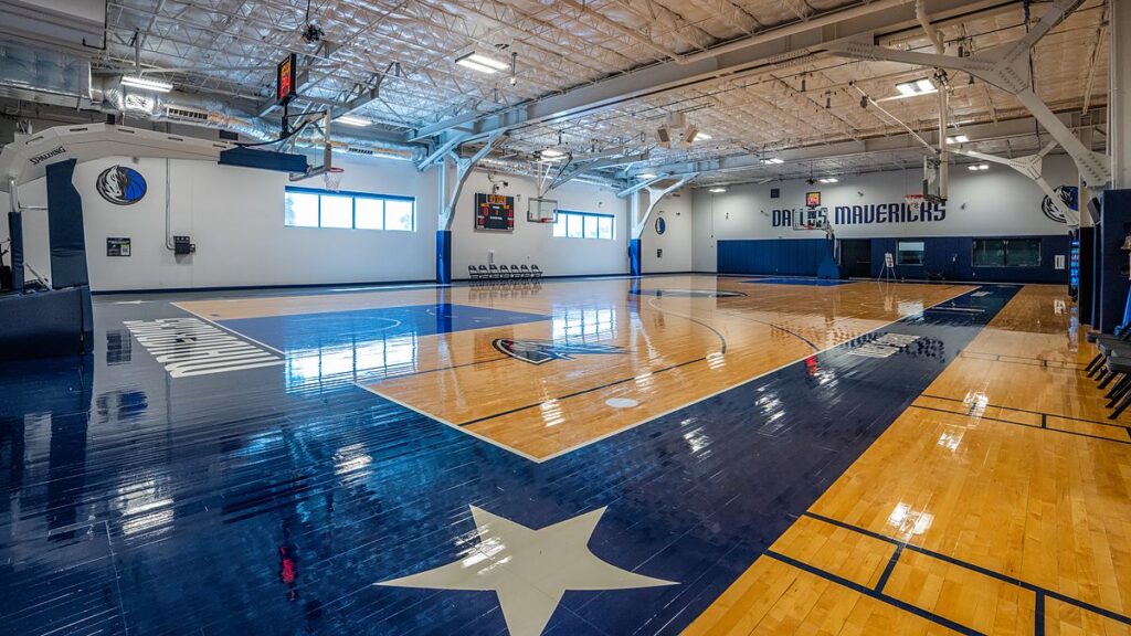 Dallas Mavericks practice court with a white star painted on navy hardwood and Dallas Mavericks lettering on the far wall.