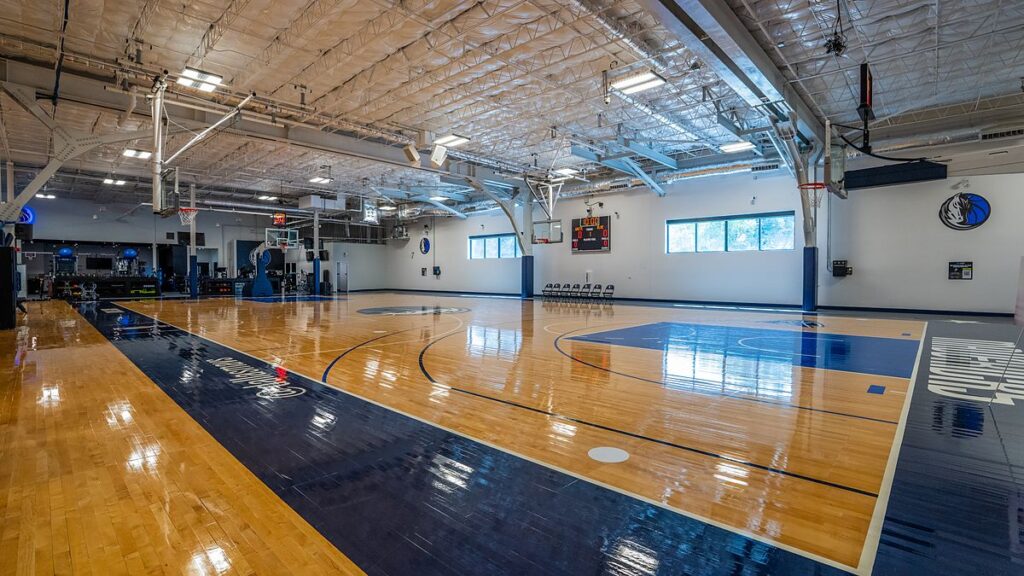 Dallas Mavericks practice court with polished hardwood, navy paint, and new windows along the far wall.