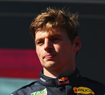Red Bull driver Max Verstappen purses his lips and looks off to the side while wearing his race suit.
