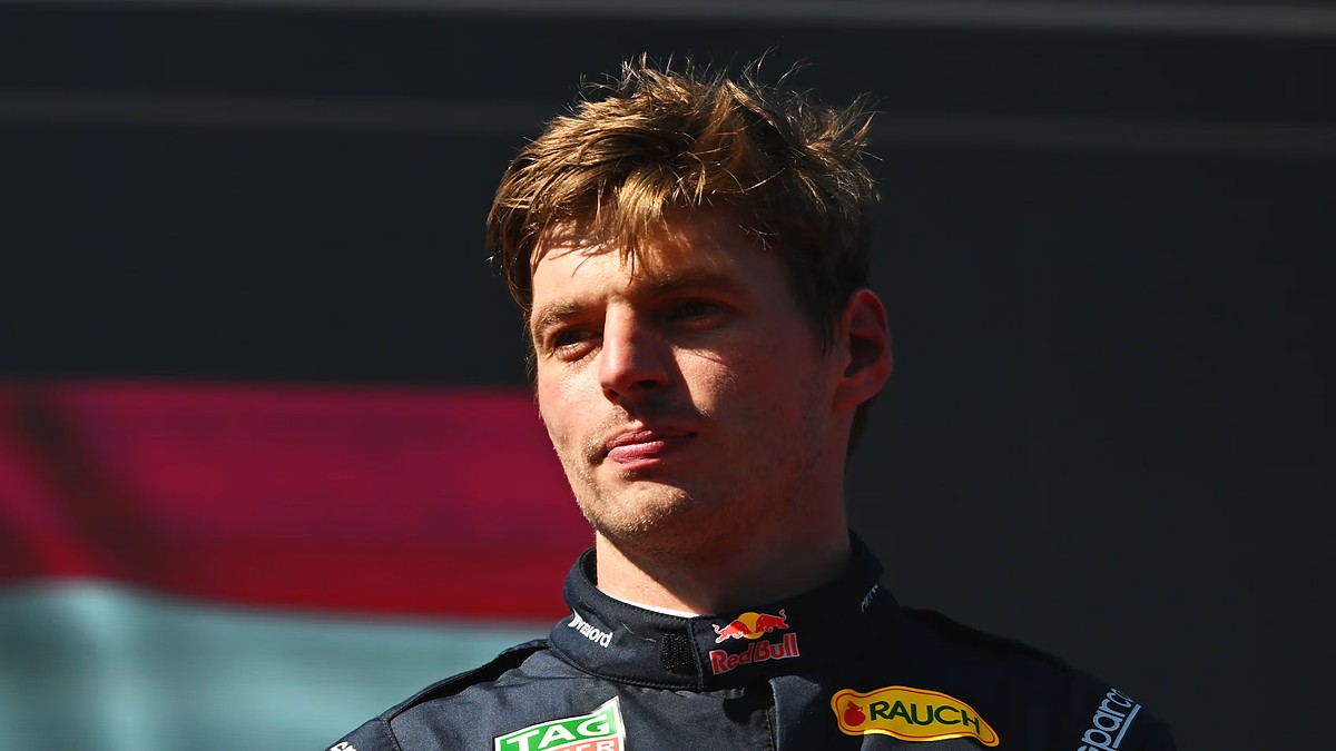 Red Bull driver Max Verstappen purses his lips and looks off to the side while wearing his race suit.