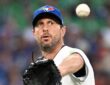 Toronto Blue Jays starting pitcher Maxwell Scherzer reaches out with his glove as a baseball flies toward him.