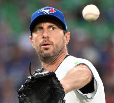 Toronto Blue Jays starting pitcher Maxwell Scherzer reaches out with his glove as a baseball flies toward him.