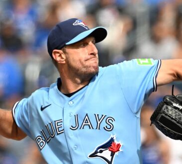 Toronto Blue Jays starting pitcher Maxwell Scherzer winds up to deliver a pitch in a light blue Blue Jays jersey.