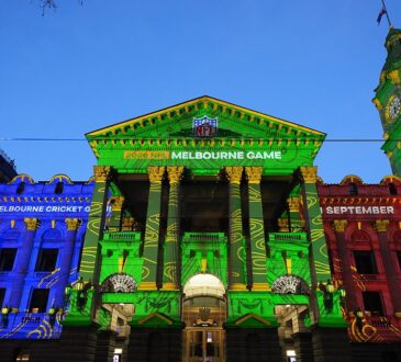 Melbourne Town Hall glows in blue, green, and red projections promoting the NFL Melbourne Game between the Rams and 49ers.