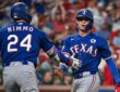 Texas Rangers pinch runner Michael Helman slaps hands with right fielder Brandon Nimmo after scoring against the Cardinals.
