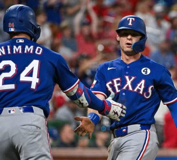 Texas Rangers pinch runner Michael Helman slaps hands with right fielder Brandon Nimmo after scoring against the Cardinals.
