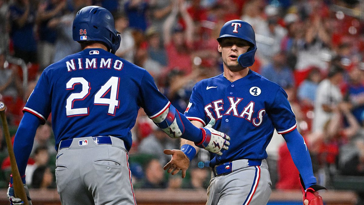 Texas Rangers pinch runner Michael Helman slaps hands with right fielder Brandon Nimmo after scoring against the Cardinals.