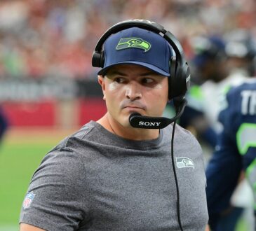 Seattle Seahawks head coach Michael Macdonald glances to his left on the sideline while wearing a headset.