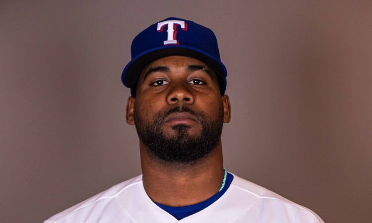 Texas Rangers pitcher Michel Otañez poses for a portrait in his home uniform against a gray backdrop.