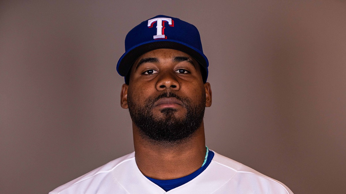 Texas Rangers pitcher Michel Otañez poses for a portrait in his home uniform against a gray backdrop.