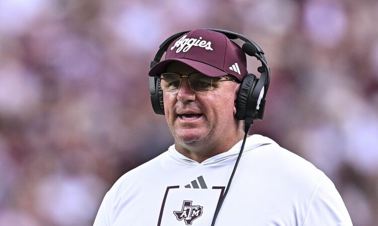 Texas A&M head coach Mike Elko wears a headset on the sideline during a game.