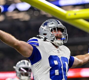 Dallas Cowboys tight end Mitch Van Vooren spreads his arms and holds up the ball after scoring a touchdown.