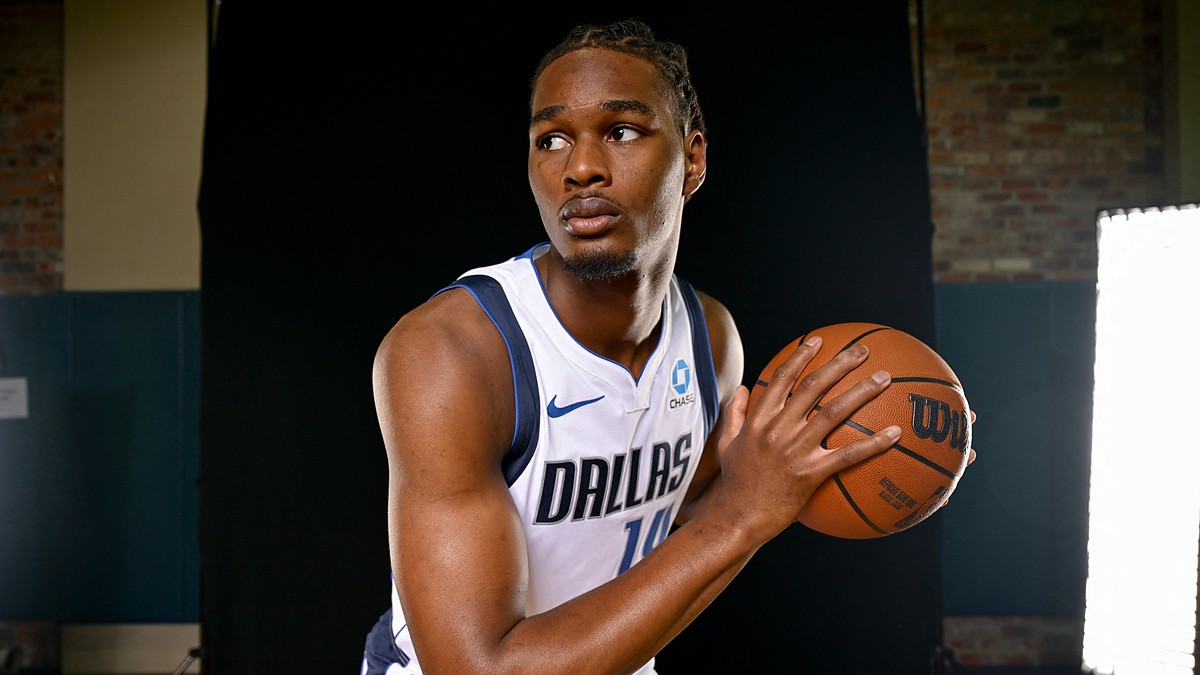 Dallas Mavericks forward Morez Johnson Jr. holds a basketball and looks to his right in a white home jersey.