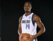 Dallas Mavericks forward Morez Johnson Jr. poses with a basketball in a white home jersey against a black backdrop.