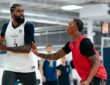 Dallas Mavericks forward Naji Marshall holds the ball as a teammate in a red practice jersey defends him.