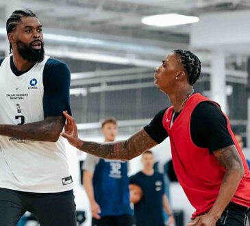Dallas Mavericks forward Naji Marshall holds the ball as a teammate in a red practice jersey defends him.