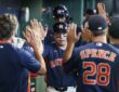 Houston Astros players Nick Allen and LaMonte Wade Jr. slap hands with teammates in the dugout after scoring.