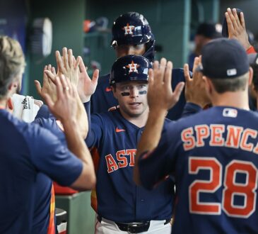 Houston Astros players Nick Allen and LaMonte Wade Jr. slap hands with teammates in the dugout after scoring.
