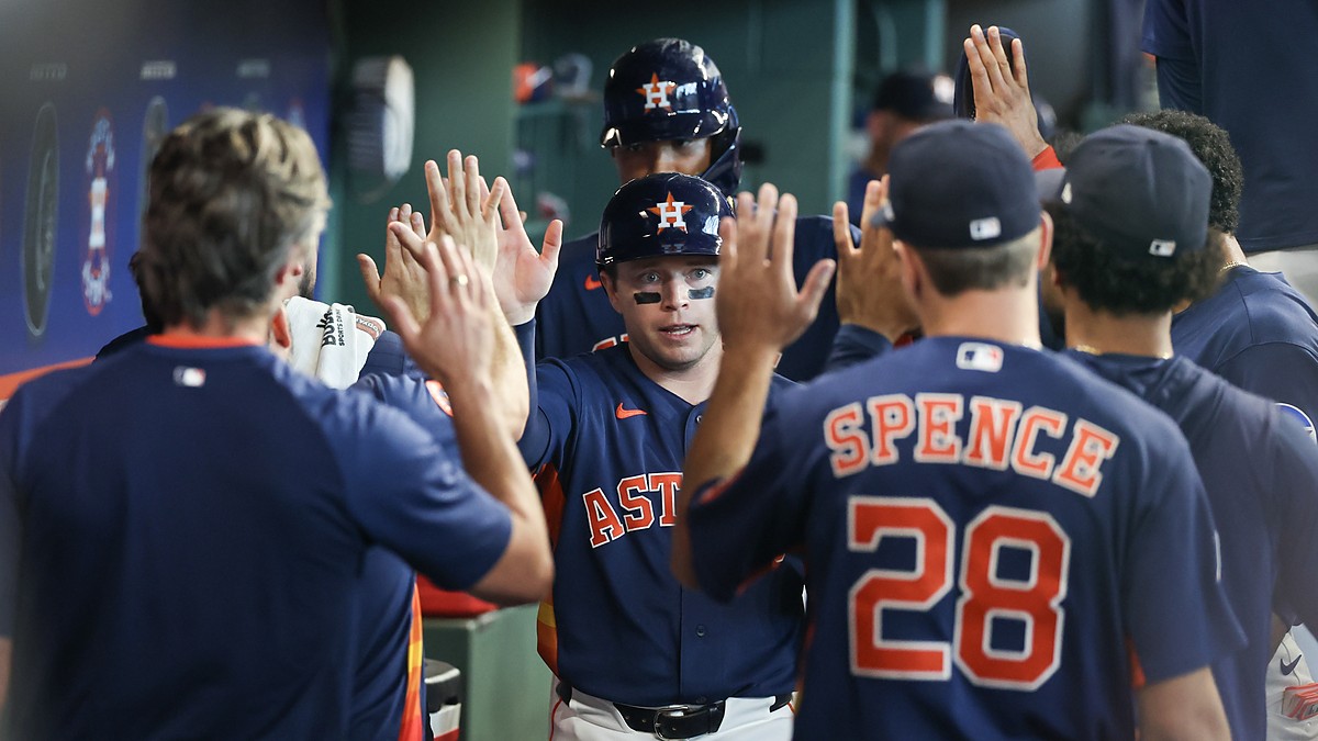 Houston Astros players Nick Allen and LaMonte Wade Jr. slap hands with teammates in the dugout after scoring.