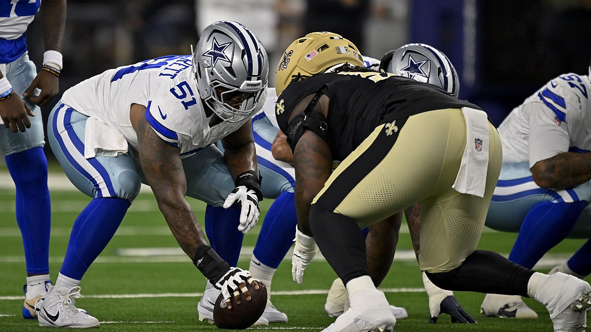 Dallas Cowboys guard Nick Leverett grips the ball in a three-point stance across the line from a New Orleans Saints defender.